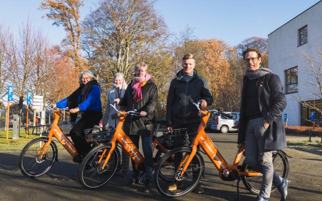 Het schepencollege met enkele oranje e-bikes van Donkey Republic aan het Sociaal Huis