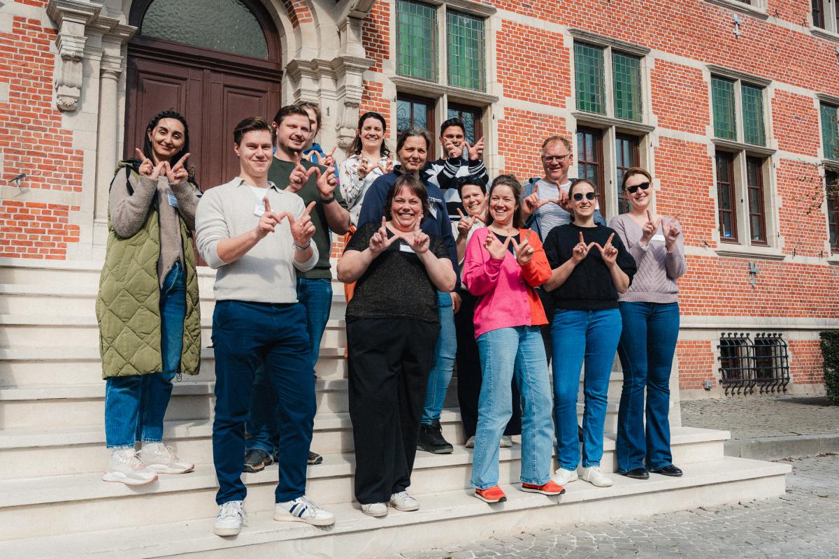 medewerkers van het lokaal bestuur Wuustwezel maken een W met hun handen op de trappen van het gemeentehuis
