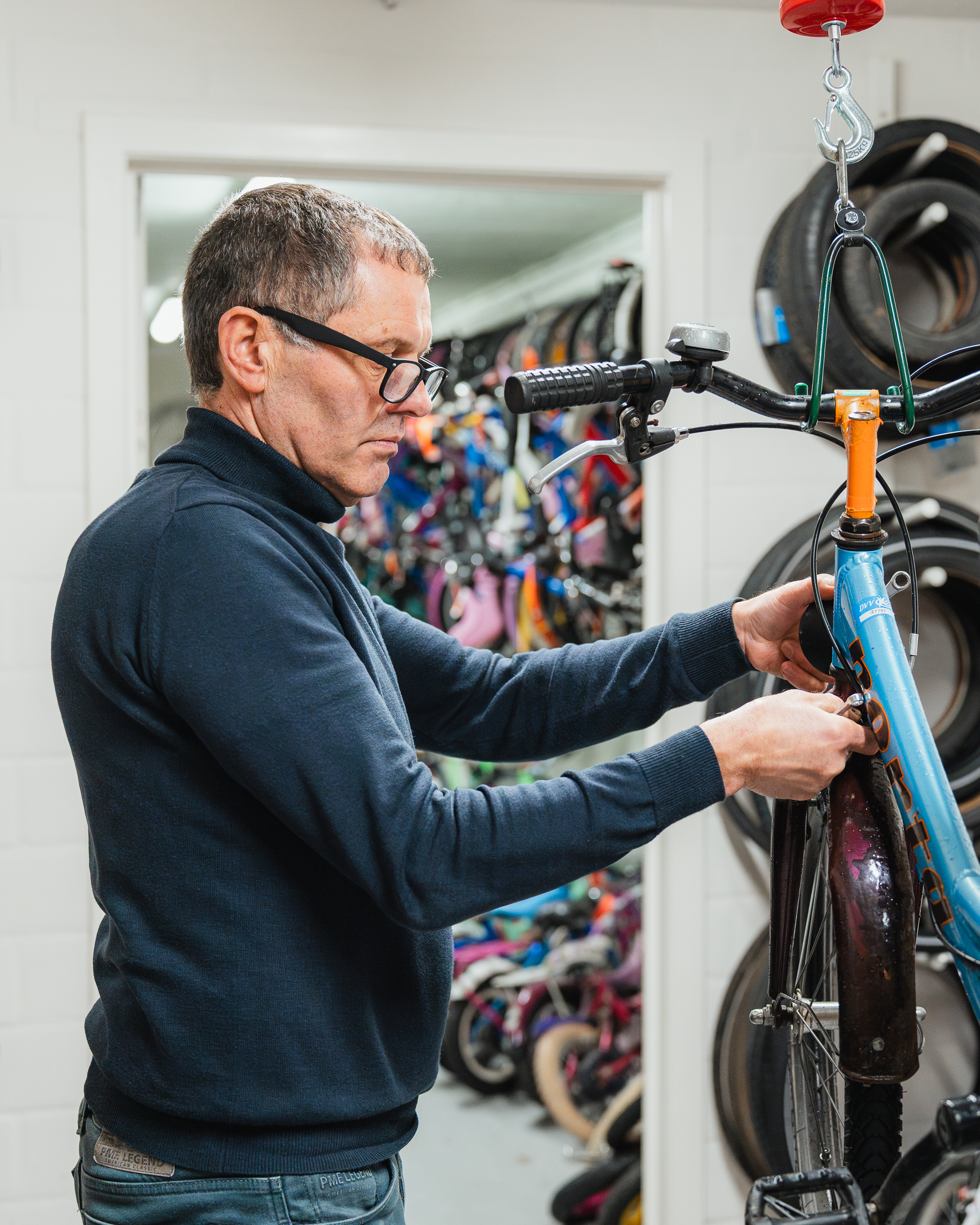 Een vrijwilliger werkt aan een kinderfiets in de Fietsbieb