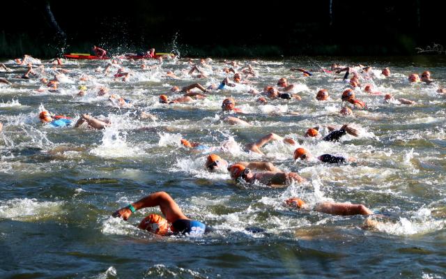 Deelnemers van de triatlon gaan zwemmen, fietsen en hardlopen