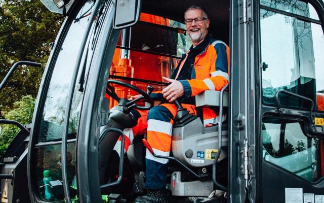 een lachende chauffeur in een graafmachine