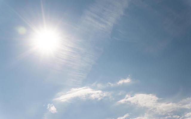 Foto van een fel brandende zon aan een blauwe hemel