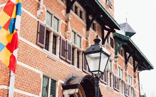 Detail van de achtergevel van het gemeentehuis met een lantaarnpaal en de gemeentevlag