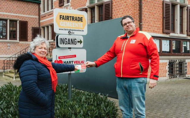 Een sticker voor 2024-2026 van het Rode Kruis wordt bevestigd aan het infopaneel Hartveilige Gemeente
