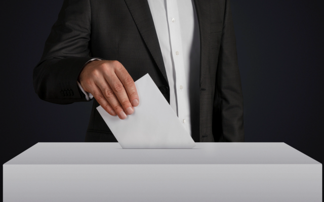een man deponeert een wit papiertje in een stemdoos