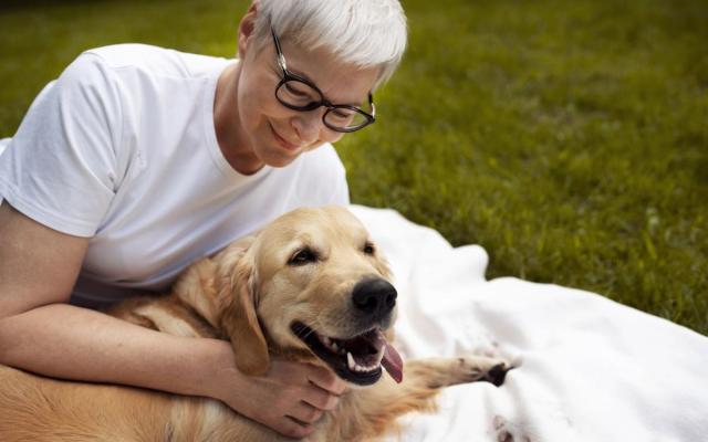 een oudere vrouw knuffelt haar hond