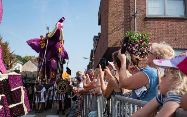 Kijklustigen nemen foto's van een passerende praalwagen tijdens Bloemencorso Loenhout 2023