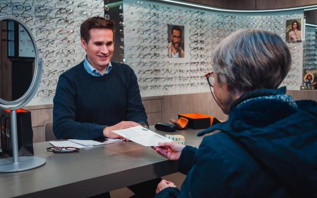 eindejaarsactie 2023: een klant in een brillenwinkel geeft haar spaarkaart aan de winkelier