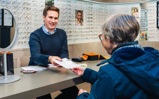 Opticien De Leersnijder overhandigt spaarzegels aan een klant