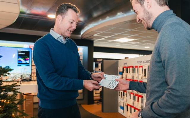 Een verkoper van PCS Computers in Wuustwezel overhandigt een volle spaarkaart aan een klant