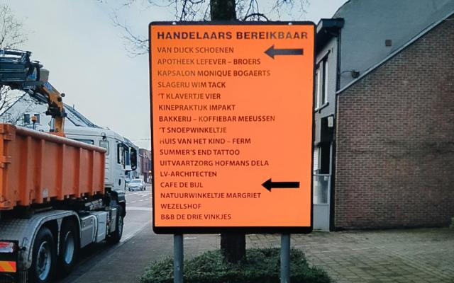 oranje verkeersbord met pijlen en een overzicht van de handelaars in het centrum