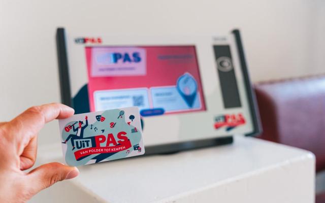 iemand houdt zijn UiTPAS voor een UiTPAS-zuil