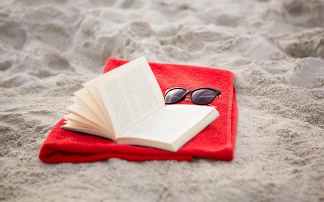 een open boek en een zonnebril op het strand