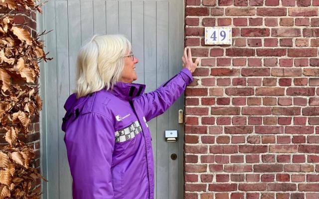 een gemeenschapswacht staat voor een woning met huisnummer 49