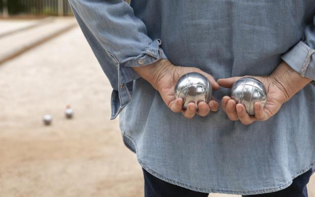 een persoon houdt twee petanqueballen in zijn handen