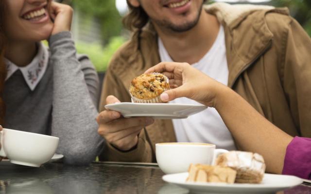 closeup van een vrouw die een cupcake deelt met andere tafelgasten