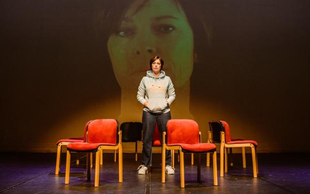 actrice Stefanie Moens op een podium met rond haar enkele lege stoelen