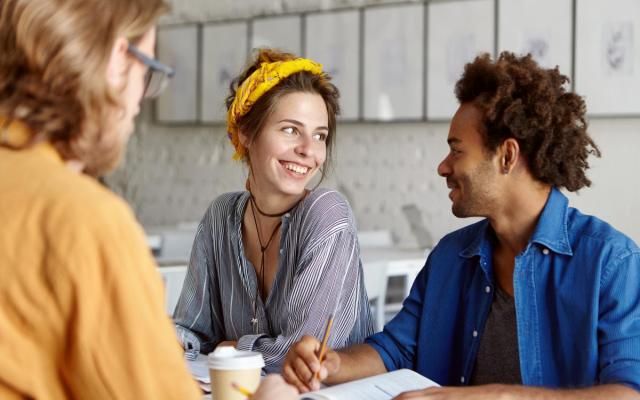 drie personen van verschillende culturen praten met elkaar aan een tafeltje