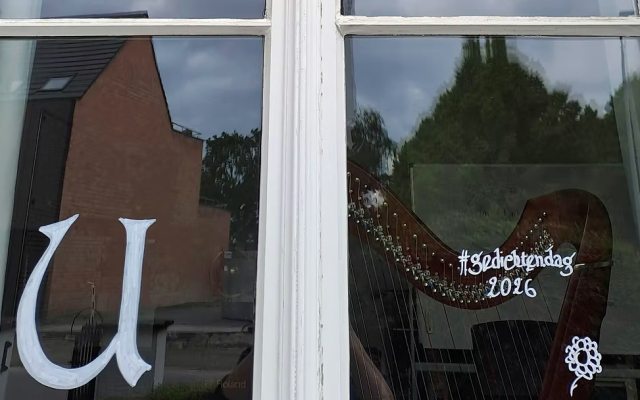 een venster van de gemeentelijke kunstacademie in Wuustwezel met de letters haiku op geschilderd