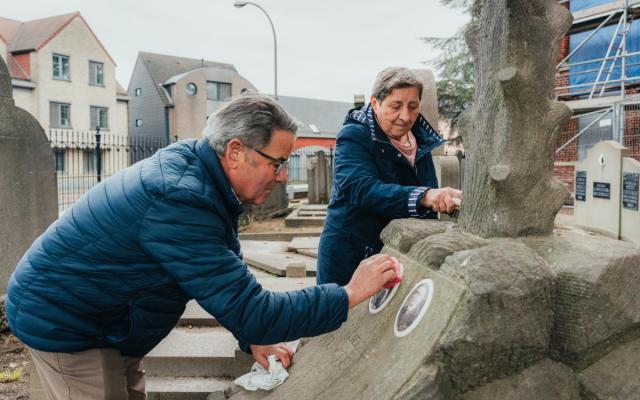 Jan Koyen en Liliane Vanhove van de cultuurraad reinigen een oud graf op de begraafplaats van Wuustwezel