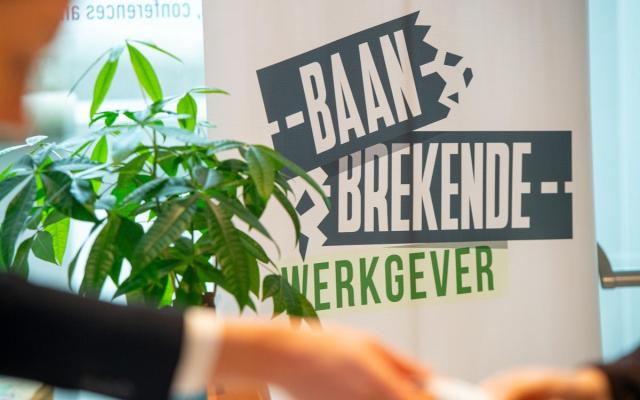 'Baanbrekende Werkgever' op een banner in een kantoorruimte