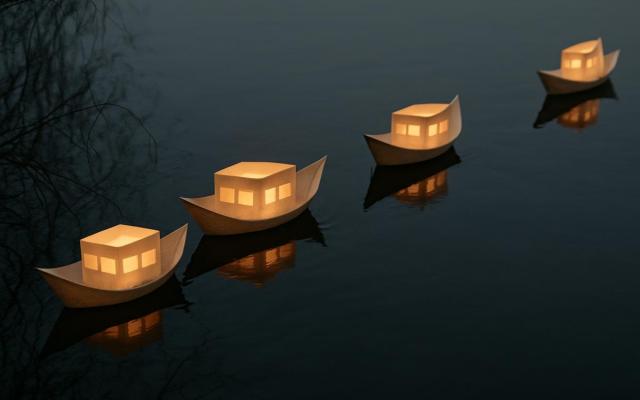papieren bootjes met een lichtje in op het water
