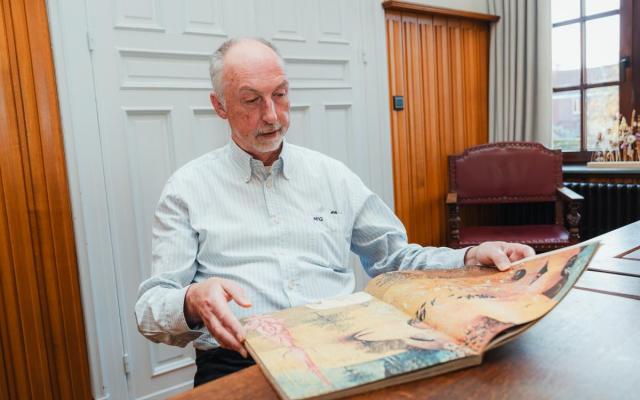 Dr. Eric De Bruyn bekijkt een boek over schilderwerken van Jheronimus Bosch