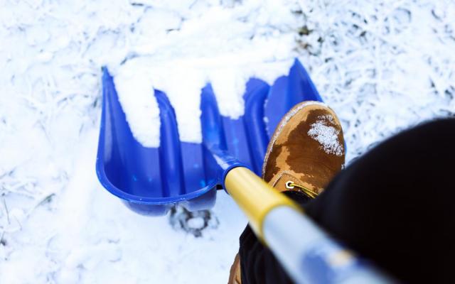 detailfoto van een man die sneeuw ruimt met een grote schop