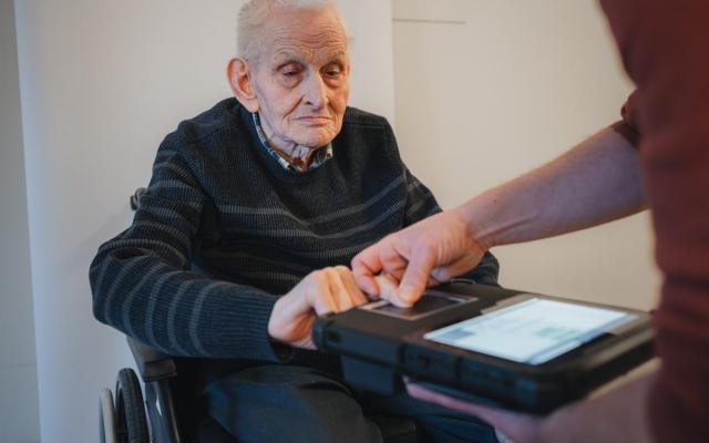een bewoner van woonzorgcentrum Amandina in Gooreind laat zijn vingerafdrukken scannen door de Mobio-kit voor de aanvraag van een nieuwe identiteitskaart
