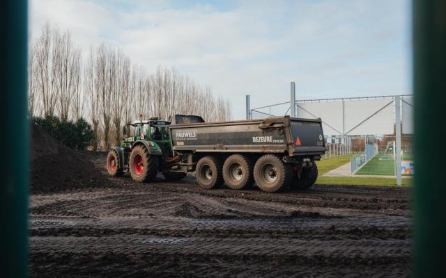 stapels zand en een traktor naast het voetbalterrein op sportpark Kattegat