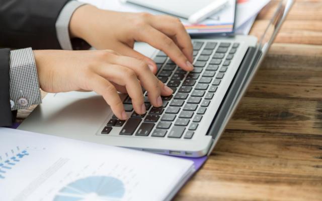 detailfoto van een man die aan het werk is op een laptop met financiële documenten naast de computer
