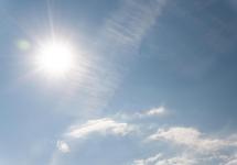 Foto van een fel brandende zon aan een blauwe hemel