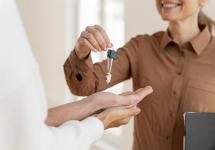 Een makelaar bezorgt sleutels van een woning aan nieuwe huurders
