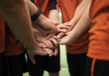 close-up van een jeugdsportteam dat de handen bij elkaar steekt