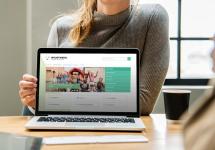 een vrouw toont een geopende laptop met de website van de gemeente Wuustwezel