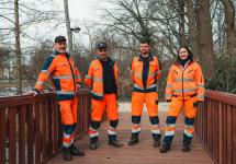 Vier medewerkers van de bouwdienst op het nieuwe bruggetje in het gemeentepark
