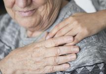 closeup van een hand op de schouders van een oudere vrouw