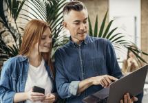 een man en vrouw in informele kledij kijken samen op een scherm van een laptop