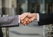 close-up van twee personen in formele kledij die elkaars hand schudden