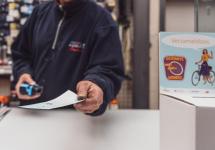 een winkelier aan zijn verkoopstoog toont een stempelkaart van Gerinkel naar de Winkel