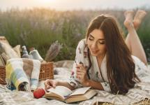 een vrouw leest een boek op een dekentje in een bloemenveld