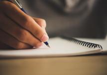 closeupfoto van een hand die een pen vasthoudt boven een notitieboek