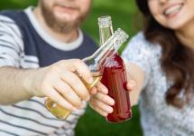 twee personen tonen hun drankje in een glazen fles