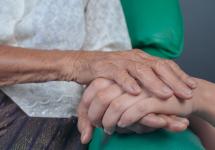 een hand van een jonge persoon houdt de hand vast van een oude vrouw