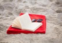 een open boek en een zonnebril op het strand