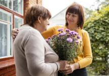 een dame schenkt een boeket bloemen aan haar oudere buurvrouw