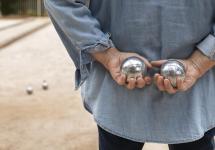 een persoon houdt twee petanqueballen in zijn handen